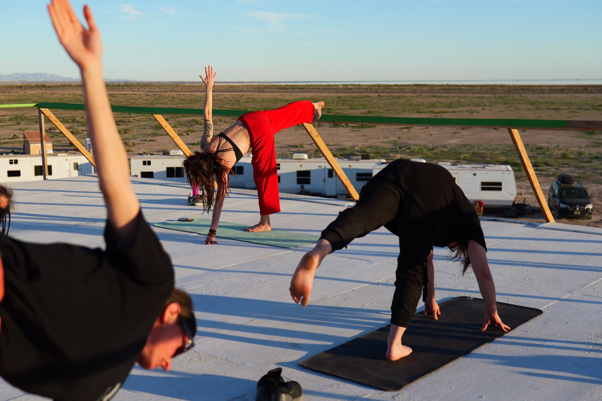 Julia in a standing split with one arm raised as students move around her