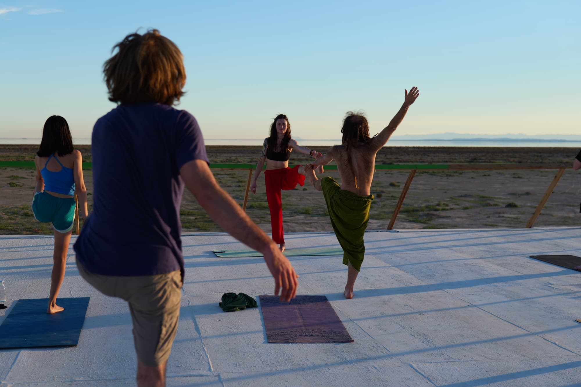Julia guiding a student into a standing balance at sunset