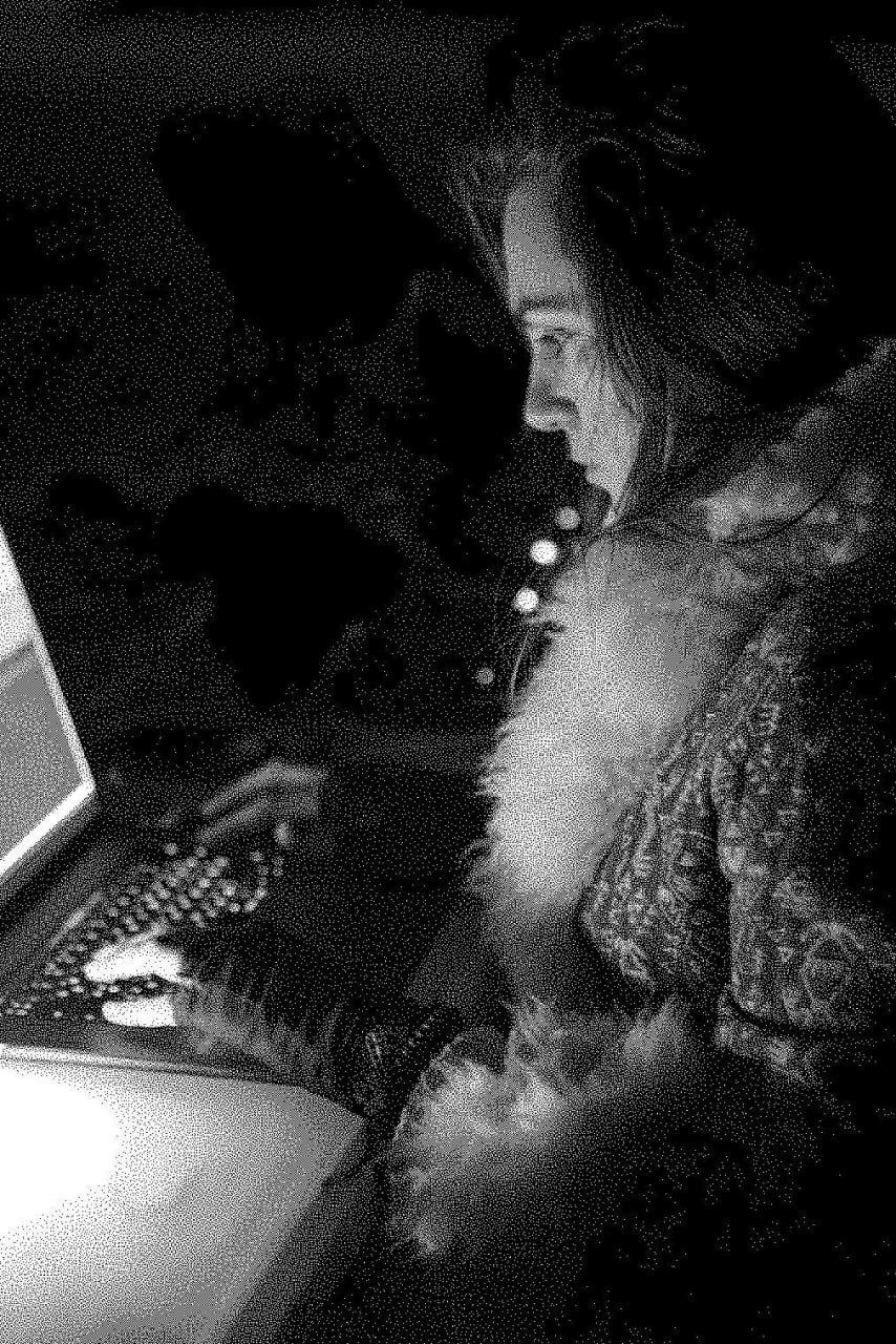 Julia at a laptop in the dark, lit by the screen